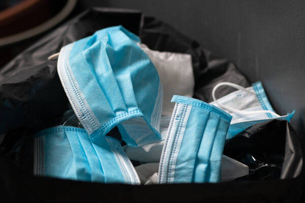 Disposing of a used mask in the trash By leaving unhygienic There may be a spread of harmful germs and viruses. Healthcare concepts. Blue mask.