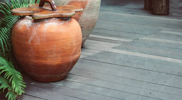 Old jar placed on a wooden floor. For storing Thai food and water. copy space. Selective focus.