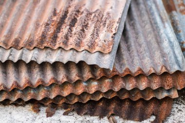 Yere yerleştirilmiş paslı metal levhaların keskin kenarları. Yaşlı, yıpranmış, paslı galvanize edilmiş, terk edilmiş ruh halinin demir kaplama çatısı. seçici odak bulanık arkaplan. Eski.