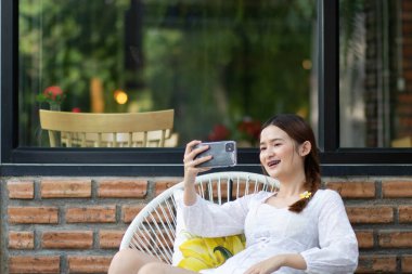 eğlence, teknoloji, tarih, insanlar ve tatil konsepti. Kendini sosyal ağ fotoğrafı için fotoğraflarken akıllı telefon dijital kamerasıyla kendi portresini yapan çekici bir kadın portresi..