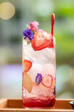 Üstünde taze pembe limonata ve nane yapraklarıyla süslenmiş ahududu ve yaz için uygun portakal bulunan tatlı suyla kaplı buz. Çilekli mojito kokteyli. Yeşil doğal bir arka plan. Şeker Yazı .