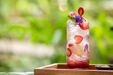 Üstünde taze pembe limonata ve nane yapraklarıyla süslenmiş ahududu ve yaz için uygun portakal bulunan tatlı suyla kaplı buz. Çilekli mojito kokteyli. Yeşil doğal bir arka plan. Şeker Yazı .