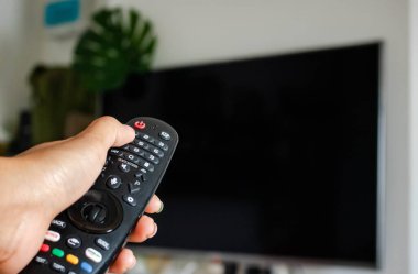 Televizyon Konsepti İzleme. Televizyon ekranının önündeki uzaktan kumandayı kullanarak. Modern Salon 'da rahatlama. Uzaktan kumandaya odaklan. Boşluğu kopyala.