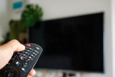 Televizyon Konsepti İzleme. Televizyon ekranının önündeki uzaktan kumandayı kullanarak. Modern Salon 'da rahatlama. Uzaktan kumandaya odaklan. Boşluğu kopyala.