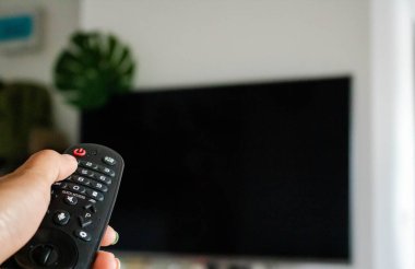 Televizyon Konsepti İzleme. Televizyon ekranının önündeki uzaktan kumandayı kullanarak. Modern Salon 'da rahatlama. Uzaktan kumandaya odaklan. Boşluğu kopyala.