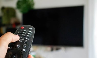 Televizyon Konsepti İzleme. Televizyon ekranının önündeki uzaktan kumandayı kullanarak. Modern Salon 'da rahatlama. Uzaktan kumandaya odaklan. Boşluğu kopyala.