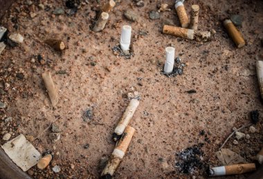 Sarı kumda sigara izmaritleri. İnsanlık sorunu. Sigara içmek, kötü alışkanlık. Nikotin bağımlılığı. Çöp. Eski tarz.