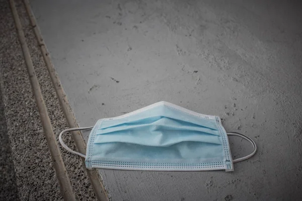 Blue disposable medical mask is on the road surface, on street. to prevent the Virus Covid-19. Concept viruses spread throughout the world. Do not throw away your used face mask. selective fofus. copy space.
