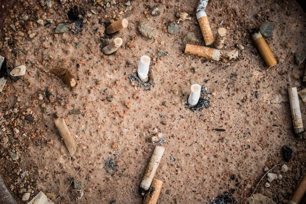 Cigarette butts in yellow sand. Problem of humanity. Cigarette smoking, bad habit. Nicotine addiction. Garbage. vintage style.