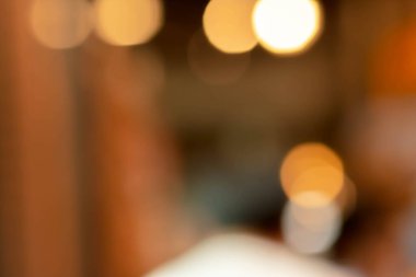 Kafe arka planında tasarımda ışık efektiyle iç mekanın soyut bulanıklığı. Bokeh 'le kafenin arka planı bulanık. turuncu, kırmızı, ışık.