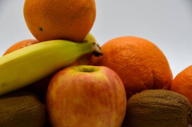 Kiviler, muzlar, portakallar ve bir elma bir arada.