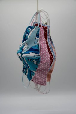 Kendi kendine dikilmiş renkli kumaş maskeler açık bir arkaplanda kuruması için asılmış.