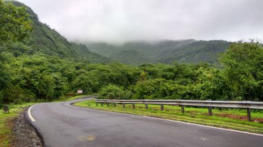 Tamhini Ghat Maharashtra yakınlarında muson mevsimi boyunca manzaralı dağları ve bulutları olan ormandaki boş yol..