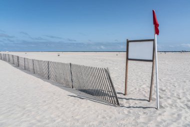 Fırtınalı eskrim ve kırmızı bayrak ile beyaz kumsalda boş beyaz tabela