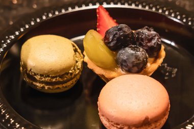 Siyah plastik bir tabak kurabiye ve meyveli turta.