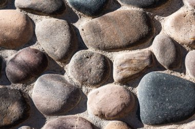 Doğal renklerde yuvarlak taşlardan oluşan taş bir duvar.