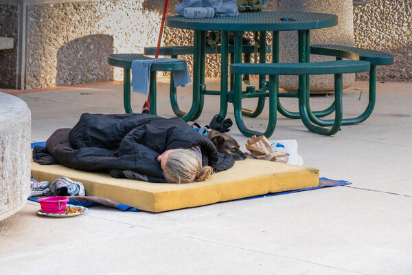 Tucson, AZ - Nov. 26, 2019: Homeless person sleeping on a foam slab in El Presidio Plaza in downtown with his dog.