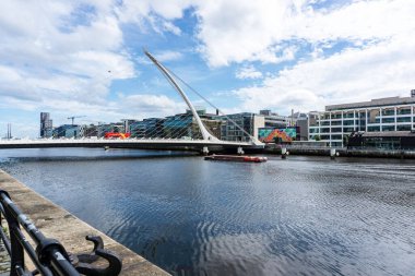  Dublin, İrlanda 'daki Liffey Nehri' ndeki Samuel Beckett Köprüsü 'nün altından geçmek üzere olan bir gezi teknesi..