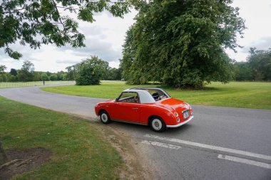 1992 model Nissan Figaro, kırmızı önden çekişli, eski model bir araba. Bu model ilk olarak 1991 yılında üretildi..