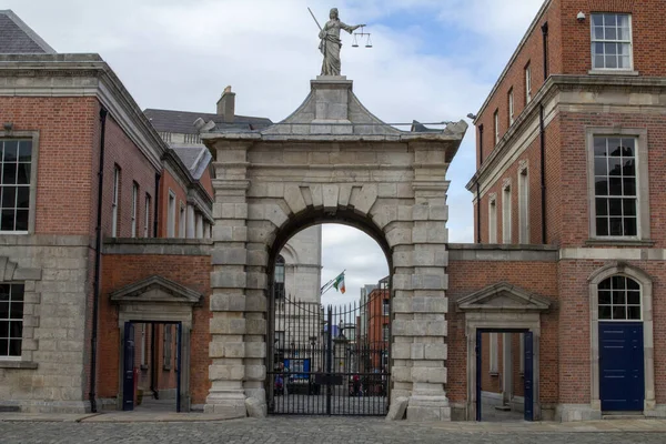 İrlanda 'nın Dublin Şatosu' nda bir elinde kılıç diğer elinde adalet terazisi olan Adalet Anıtı 'nın heykeli olan bir kapı. Arka planda İrlanda Cumhuriyeti 'nin üç rengi var..