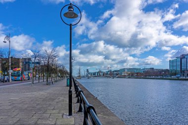 Liffey, Dublin, İrlanda boyunca uzanan Kuzey Duvar Rıhtımı, kendine özgü sokak lambaları ile popüler bir yürüyüş ve bisiklet alanı. Uzakta Jeanie Johnston Kıtlık Gemisi ve Samuel Beckett Köprüsü.