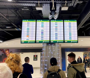 Dublin Havaalanı, İrlanda 'ya varış bölgesi. İnsanlar varış duyurusu panosunu tarıyor. .