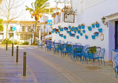 İspanya 'nın Mias kentindeki bir restoranın önündeki mavi renkli masa kumları. Duvarları çiçek sepetleriyle süslenmiş..