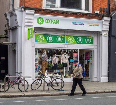Oxfam 'ın yanından geçen bir adam, Dublin, Rathmine' de bir hayır kurumu. İrlanda.
