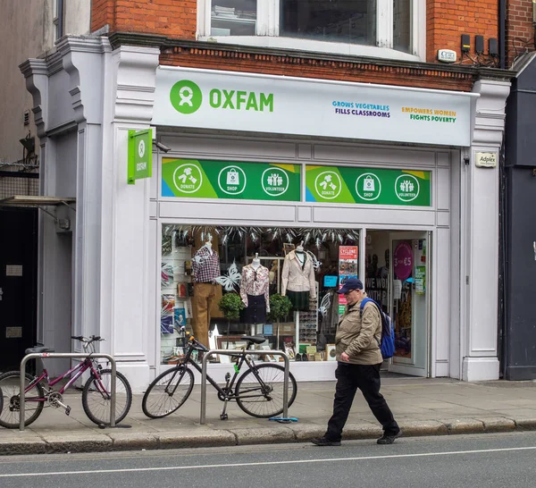 Oxfam 'ın yanından geçen bir adam, Dublin, Rathmine' de bir hayır kurumu. İrlanda.