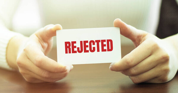 Бизнесвумен, держащая открытку с текстом Отклонено
