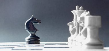 Bir satranç siyah atı rakibinin beyaz satrancının karşısında duruyor. Liderlik ve yüzleşme sembolü.