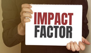 Üzerinde IMPACT FACTOR yazan bir kart tutan işadamı