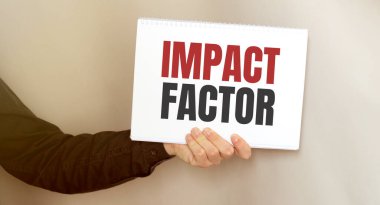 Üzerinde IMPACT FACTOR yazan bir kart tutan işadamı