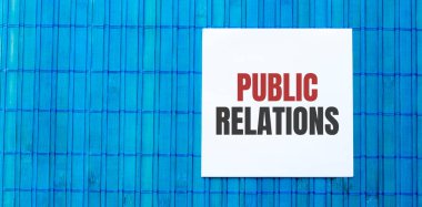 Mavi ahşap arkaplan üzerine halkla ilişkiler metni içeren boş not defteri