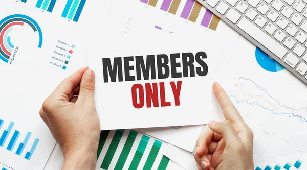 Businessman holding a card with text MEMBERS ONLY. Keyboard, diagram and white background