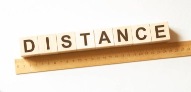 Beyaz arkaplanda tahta zemine küp şeklinde yazılmış DISTANCE kelimesi, metin veya diğer resim veya tasarım eklemek için harf blokları farklı sözcüklere ayrılır