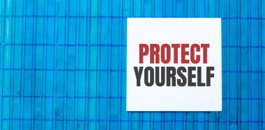 Yeşil ahşap zemin üzerinde PROTECT kendin için metin içeren boş not defteri