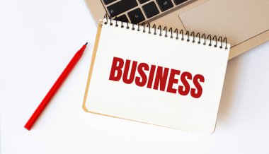 Laptop, kırmızı kalem ve beyaz arkaplanda metin BUSINESS ile not defteri