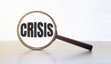 Tahta masadaki CRISIS yazılı büyüteç.