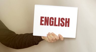 Gri arka planda ENGLISH metni olan broşür tutan adam. Tasarım için hazırlan