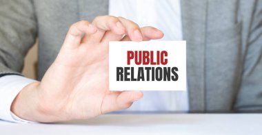 Gri arkaplanda PUBLIC ilişkili bir kart tutan adam. Tasarım için hazırlan