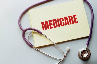 steteskop, kalemler ve beyaz zemin üzerinde MEDICARE metni ile not