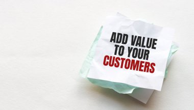 Tahta bir masanın üzerine defter ve kalem, metin için kopyalama alanı, buruşuk sarı kağıt, çalışma yeri, beyin fırtınası üzerine ADD VALUE yazan kadın el.