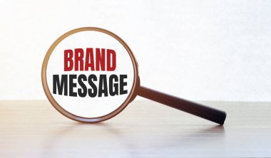 Tahta masanın üzerinde yazı markası mesajı olan büyüteç.