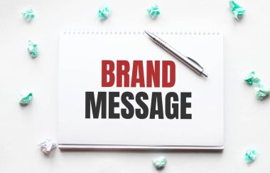 Boş çarşaf, kalem ve buruşuk kağıt toplar gri masada, düz yatıyordu. Marka Mesajı