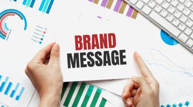 İş adamı BRAND MESAGE Klavye, diyagram ve beyaz arkaplan içeren bir kart tutuyor