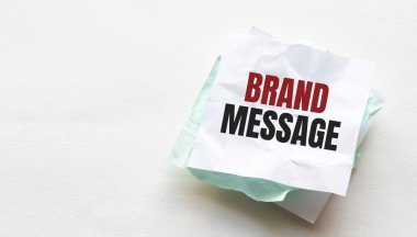 Tahta bir masanın üzerine defter ve kalem, metin için kopyalama alanı, buruşuk sarı kağıt üzerinde kadın el yazısı BRAND MESAGE, çalışma yeri, beyin fırtınası