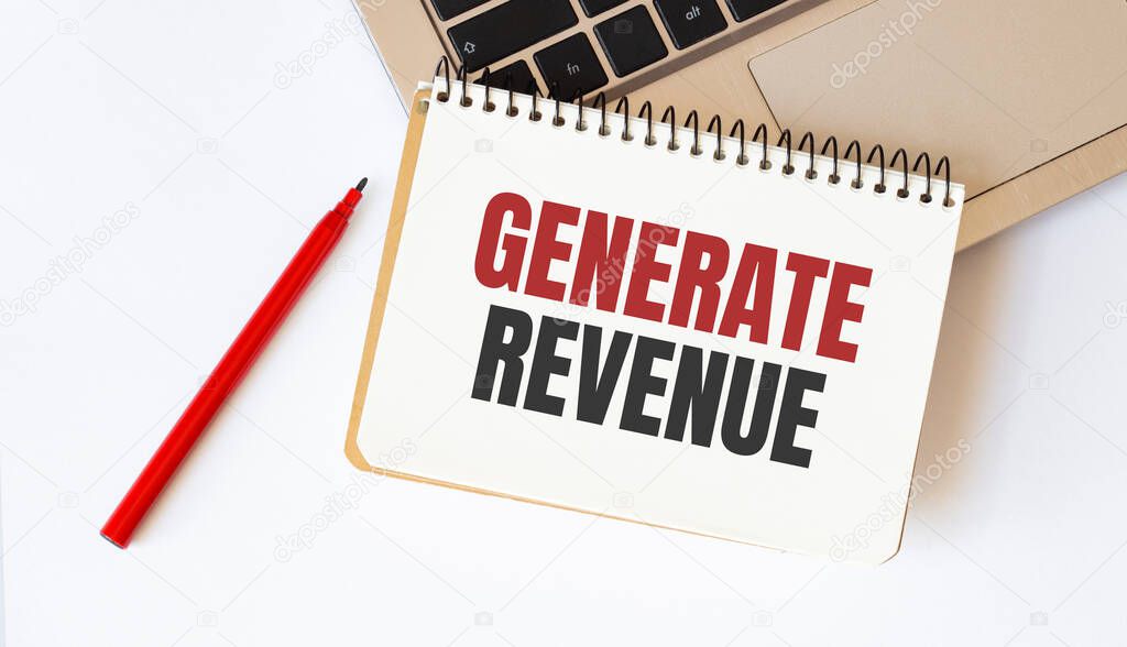 Laptop, red pen and notepad with text GENERATE REVENUE in the white background