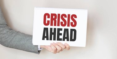 CRISIS ÖNCE yazılı bir kart tutan bir işadamı