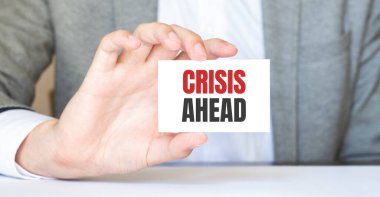 CRISIS ÖNCE yazılı bir kart tutan bir işadamı